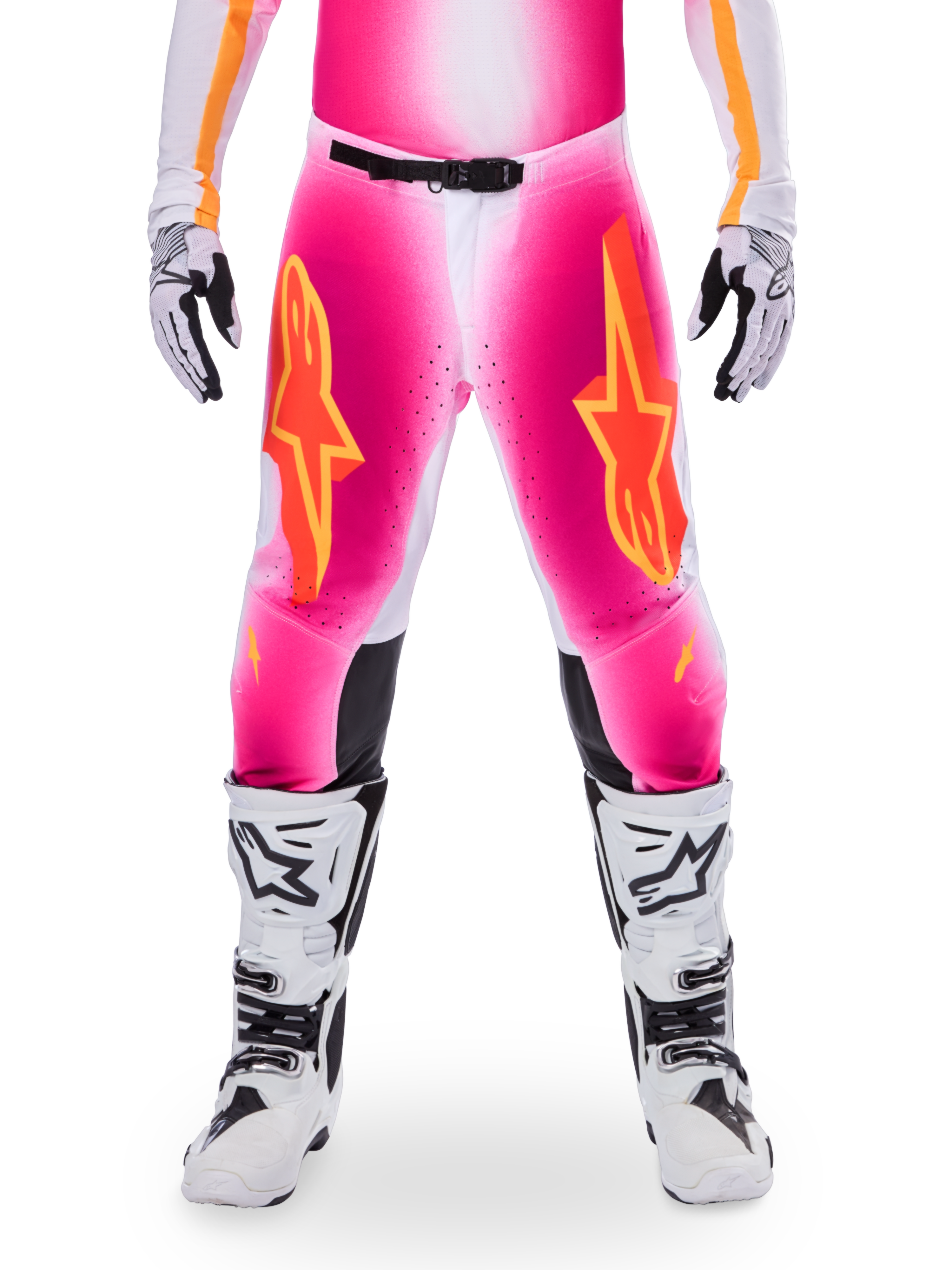 Alpinestars Limited Edition Supertech AFD MIG Pants, pantalones de motocross para carreras, rosa flúor y blanco con detalles en naranja, con grandes logotipos de estrellas en los muslos, paneles perforados y zonas de agarre negras en las rodillas, usados con botas de motocross blancas y negras