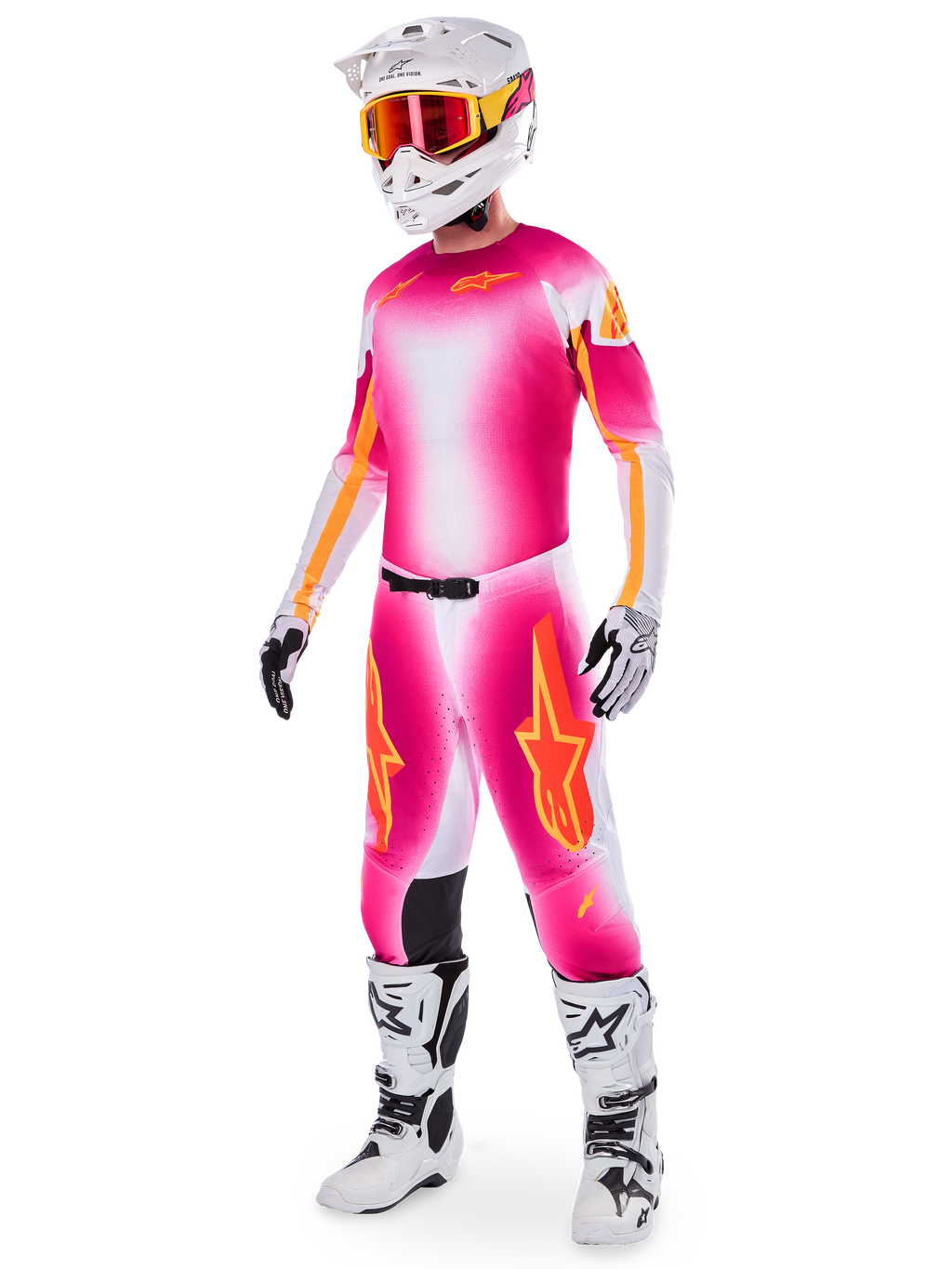 Piloto de motocross con el conjunto de equipamiento Alpinestars Supertech AFD MIG Limited Edition, jersey y pantalones con degradado en rosa flúor, blanco y naranja, casco blanco con gafas naranjas, botas blancas y negras, indumentaria profesional para conducción en tierra