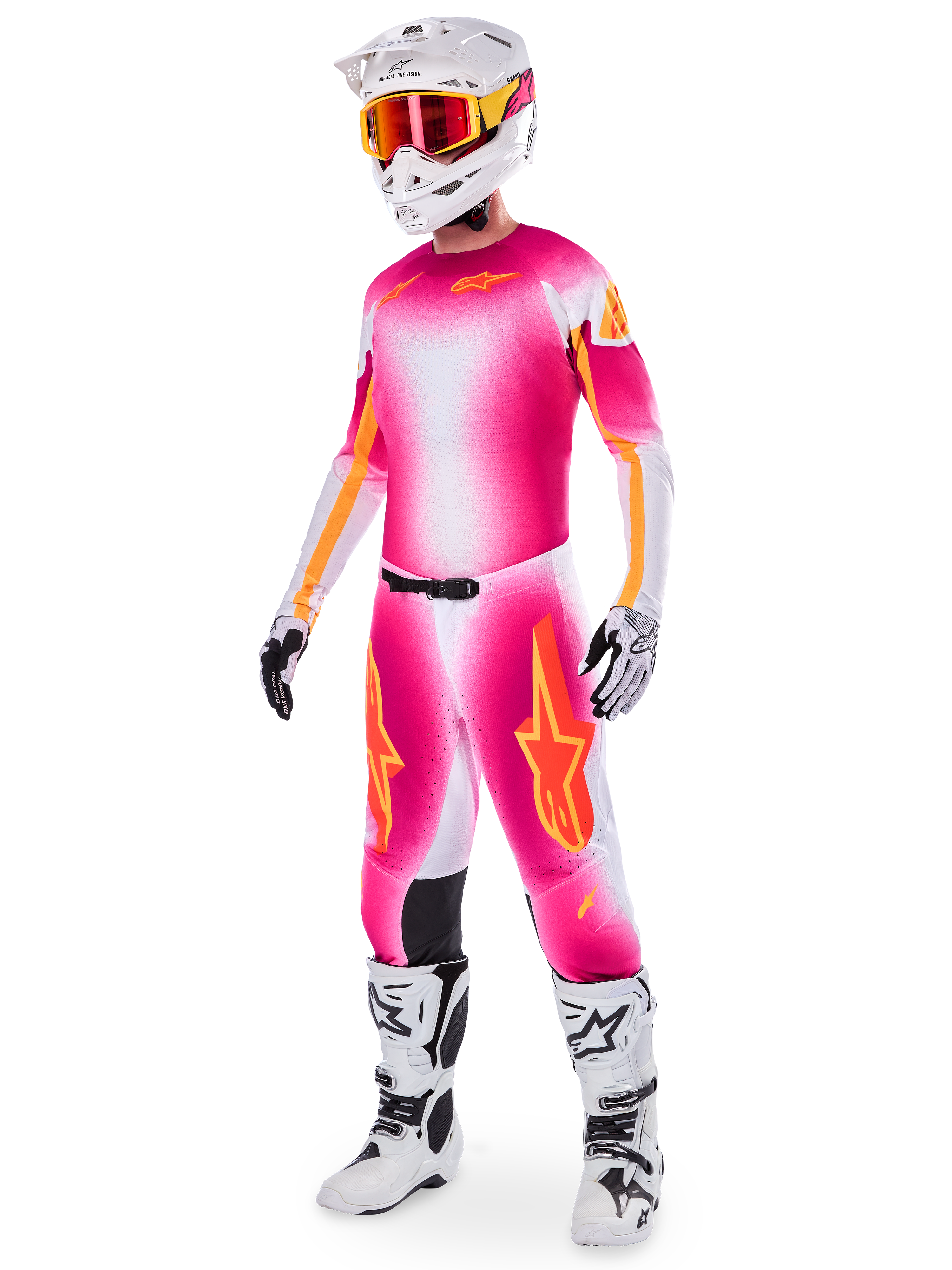 Piloto de motocross con el conjunto de equipamiento Alpinestars Supertech AFD MIG Limited Edition, jersey y pantalones con degradado en rosa flúor, blanco y naranja, casco blanco con gafas naranjas, botas blancas y negras, indumentaria profesional para conducción en tierra