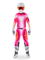 Piloto de motocross con el conjunto de equipamiento Alpinestars Limited Edition Supertech AFD MIG, camiseta y pantalones con degradado en rosa flúor y blanco con logotipos naranjas, casco blanco con gafas rojas, botas y guantes blancos y negros, atuendo de carreras profesional coordinado.