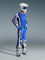 Motocross rider wearing 2026 Racer Air Portl Pants in Ucla Blue White, paired with a matching blue and white jersey, white helmet with blue goggles, and white boots, full gear set for off-road racing.