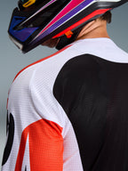 Alpinestars 2026 Racer Air Portl Jersey, jersey de motocross, multicolor con paneles blancos, negros y rojos, primer plano de la construcción de malla perforada en el hombro y la espalda para ventilación, usado con un casco de motocross colorido
