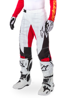 Alpinestars Limited Edition Techstar Deep Pants, pantalones de motocross, blanco, negro y rojo intenso, usados con botas y guantes blancos y negros, con paneles frontales blancos con acentos rojos y detalles laterales en negro, diseñados para carreras todoterreno de alto rendimiento