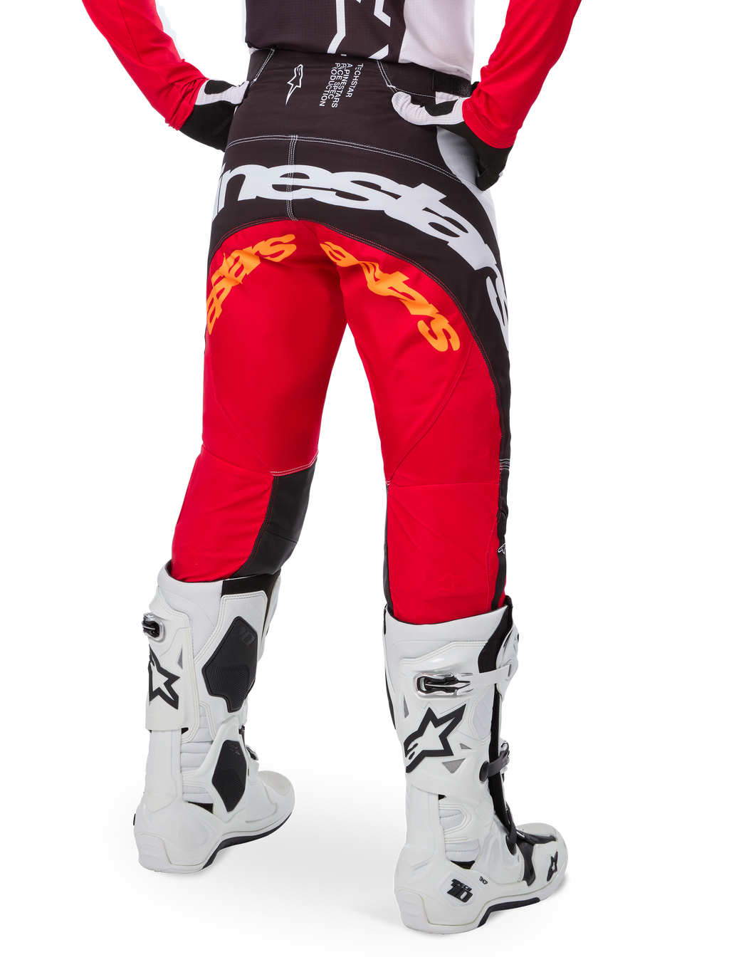 Alpinestars Techstar Deep Pants Edición Limitada, pantalones de motocross en negro, blanco y rojo intenso, vista posterior con un llamativo logo de Alpinestars en blanco sobre el asiento y detalles en naranja, usados con botas técnicas blancas para competición profesional de motocross