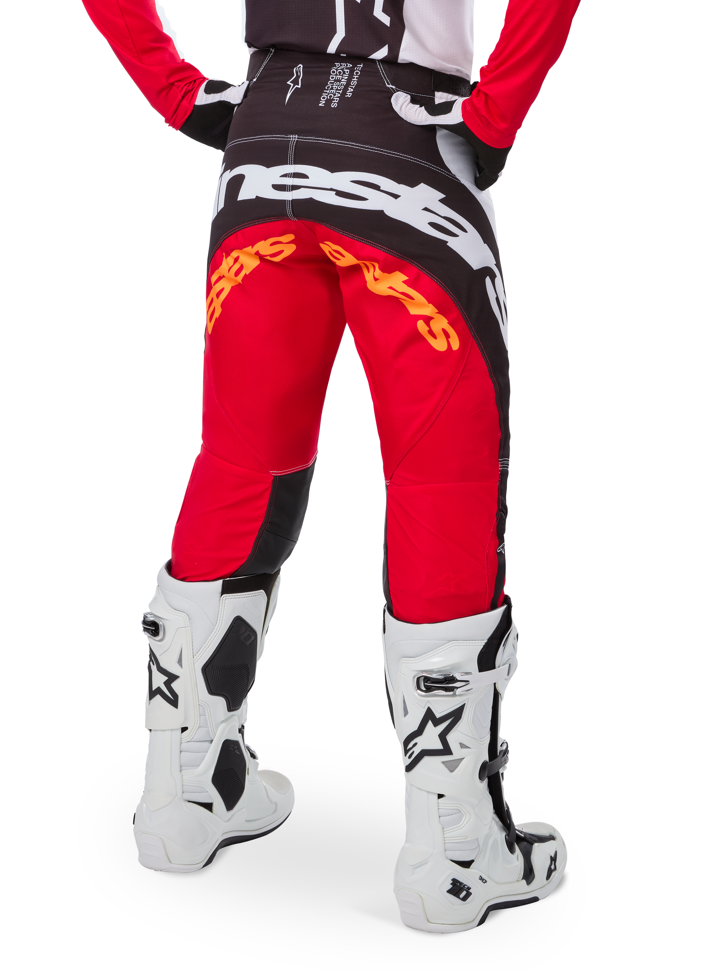 Alpinestars Techstar Deep Pants Edición Limitada, pantalones de motocross en negro, blanco y rojo intenso, vista posterior con un llamativo logo de Alpinestars en blanco sobre el asiento y detalles en naranja, usados con botas técnicas blancas para competición profesional de motocross