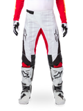 Alpinestars Limited Edition Techstar Deep Pants, pantalones de motocross en negro, blanco y rojo intenso, combinados con jersey rojo y botas y guantes blancos y negros, con paneles frontales blancos, acentos rojos en la parte interna de la pierna, paneles laterales negros, logotipos de Alpinestars en los muslos y detalles perforados con láser para ventilación.