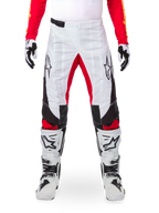 Alpinestars Limited Edition Techstar Deep Pants, pantalones de motocross en negro, blanco y rojo intenso, combinados con jersey rojo y botas y guantes blancos y negros, con paneles frontales blancos, acentos rojos en la parte interna de la pierna, paneles laterales negros, logotipos de Alpinestars en los muslos y detalles perforados con láser para ventilación.
