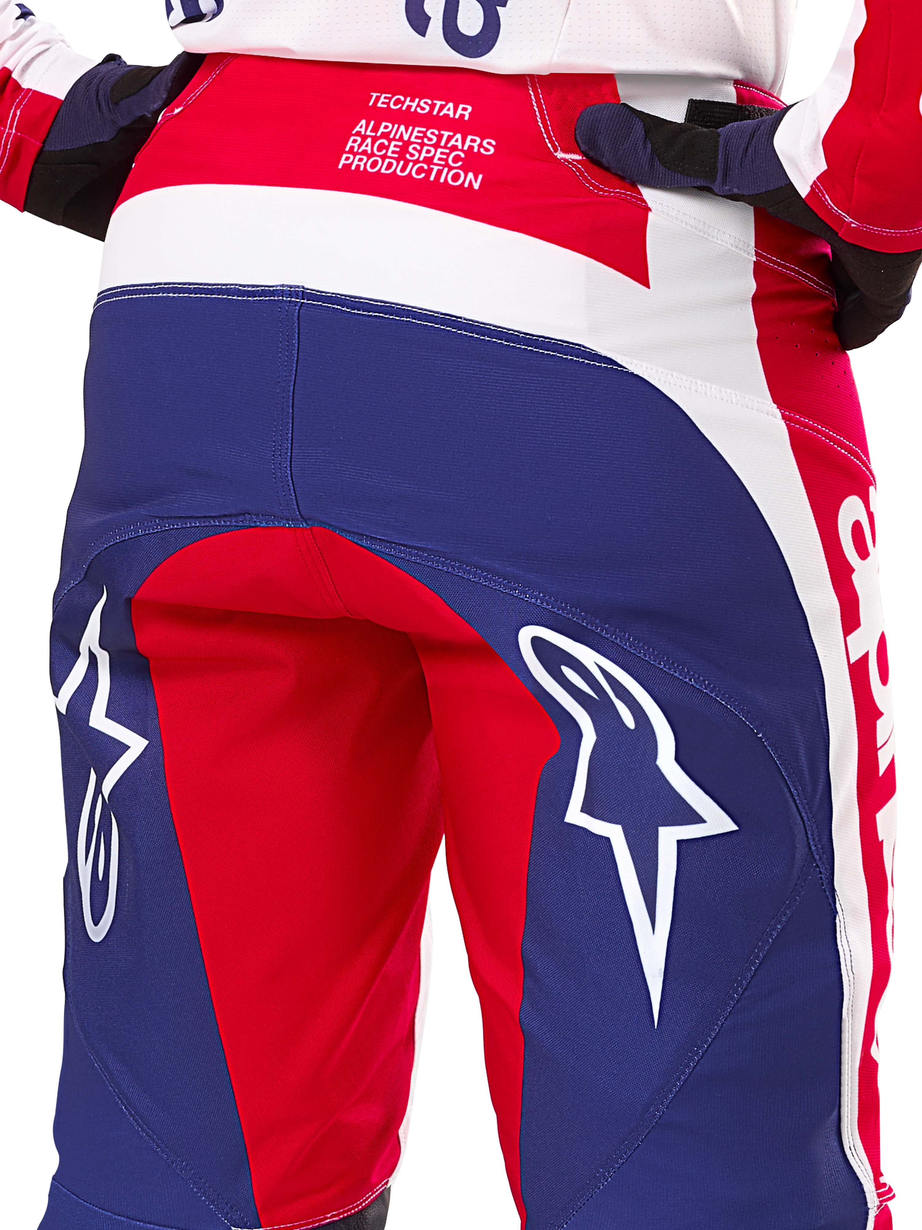 Alpinestars Limited Edition Techstar Fortitude Pants, pantalones de motocross, rojos, blancos y azules, vista trasera con grandes logotipos de estrellas blancas en el asiento y marca Techstar Race Spec, textiles de alto rendimiento para carreras todoterreno
