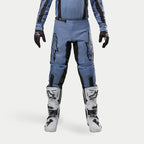 Pantalones Alpinestars Fluid Lurv 2024, pantalones de motocross, azul claro y negro, usados con botas de carreras blancas y negras y guantes a juego, con logotipos de estrellas negras en los muslos y diseño ergonómico para rendimiento todoterreno