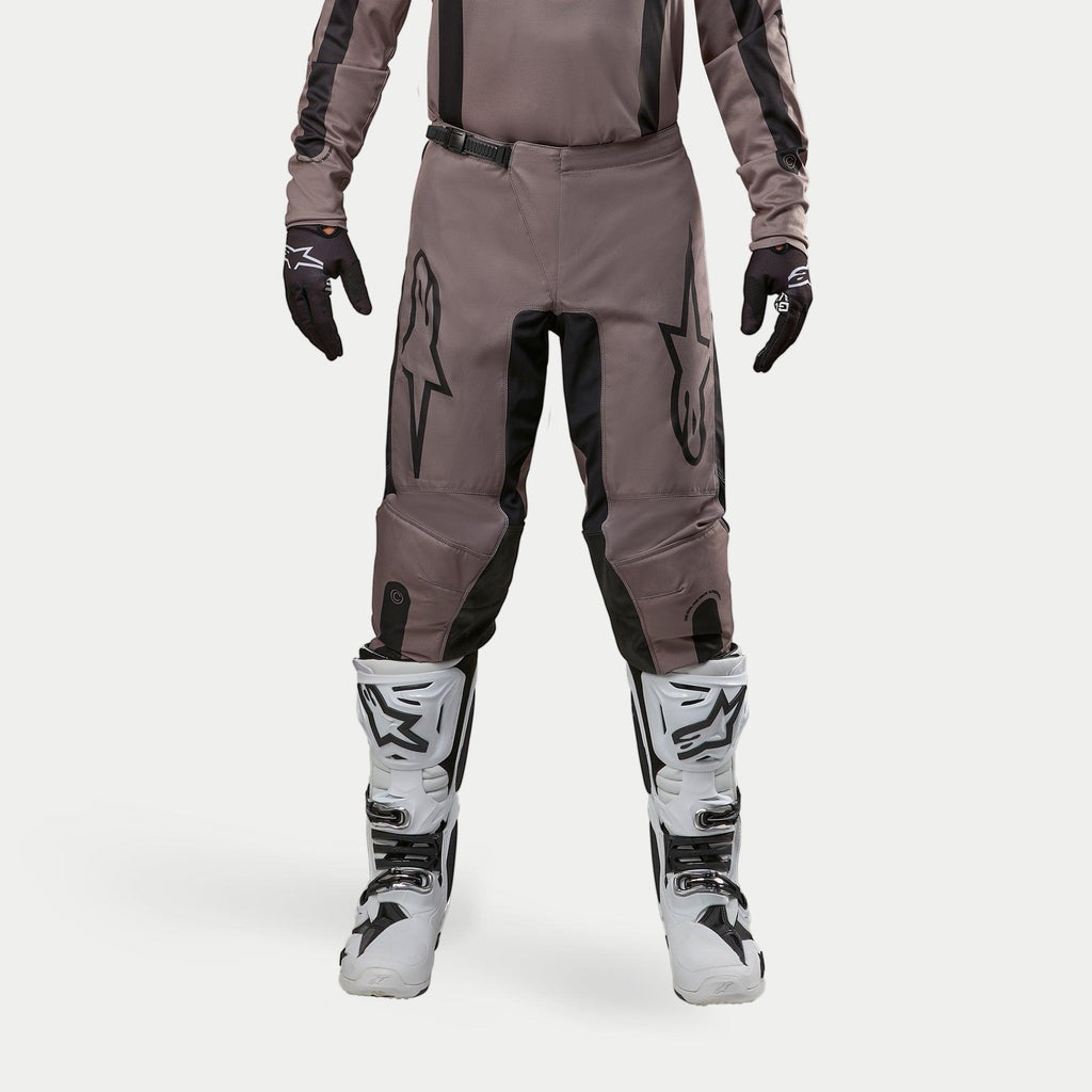Pantalones Alpinestars Fluid Lurv 2024, pantalones de motocross, Mud Black, usados con jersey a juego, guantes negros y botas blancas, con logotipos negros grandes en los muslos, ajuste ergonómico y material duradero para carreras fuera de carretera
