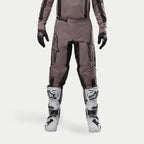 Pantalones Alpinestars Fluid Lurv 2024, pantalones de motocross, Mud Black, usados con jersey a juego, guantes negros y botas blancas, con logotipos negros grandes en los muslos, ajuste ergonómico y material duradero para carreras fuera de carretera