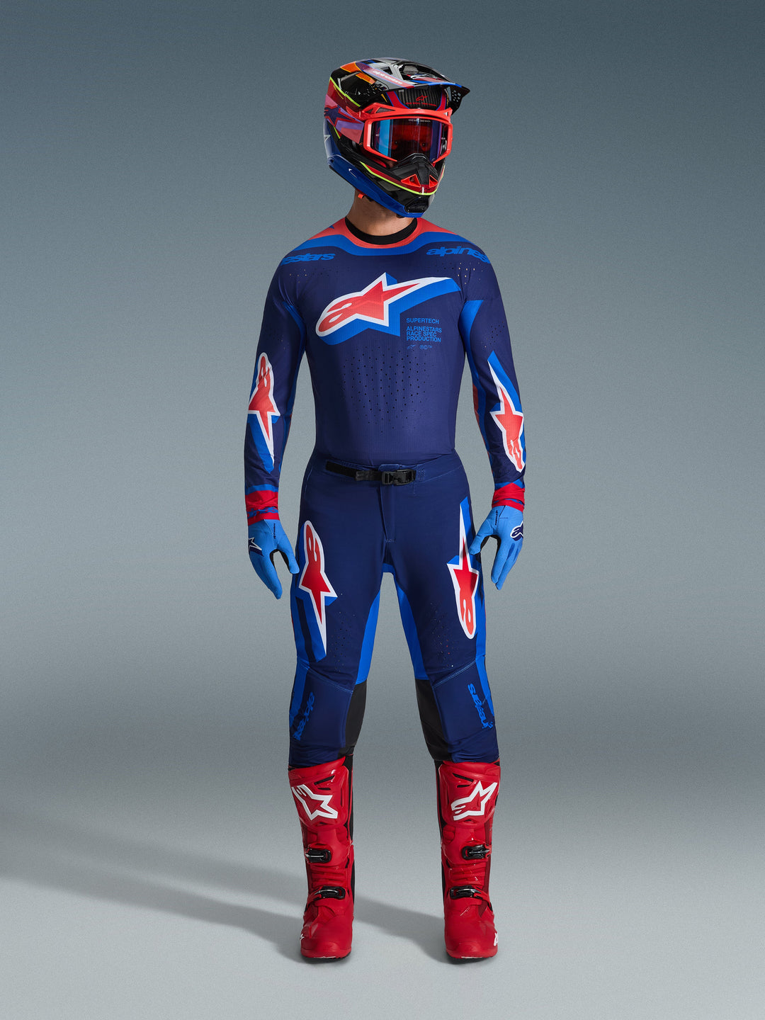 Conjunto de equipamiento Supertech Vista 2026, traje completo de competición de motocross, camiseta y pantalones azul oscuro con logotipos de estrellas rojas y blancas, casco multicolor con gafas rojas, guantes azul claro y botas rojas brillantes, equipo de MX de nivel profesional