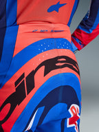 Close-up of Alpinestars 2026 Supertech Vista Pants, Motocross Pants, Hot Coral and Cobalt Blue, featuring a large black Alpinestars graphic on the seat, laser-cut ventilation holes, and 'SUPERTECH' branding on the back waist, professional-grade racing apparel.