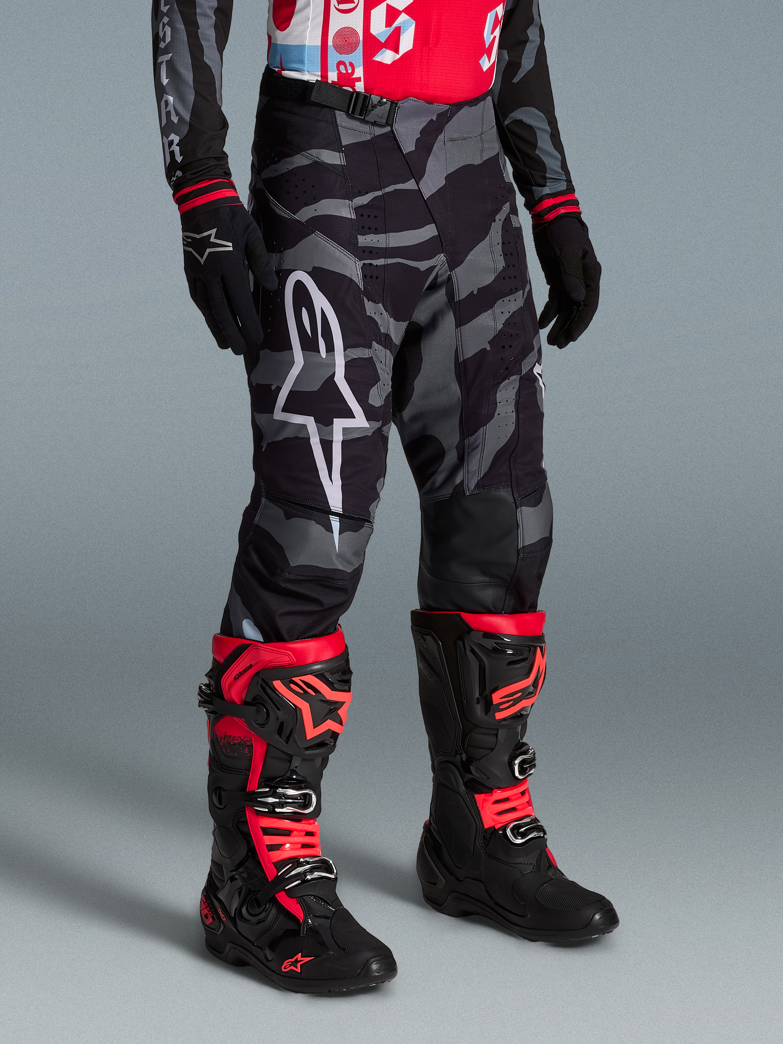 Pantalones Techstar Beast Coast Edición Limitada en camuflaje negro y gris con botas de motocross en rojo vibrante.