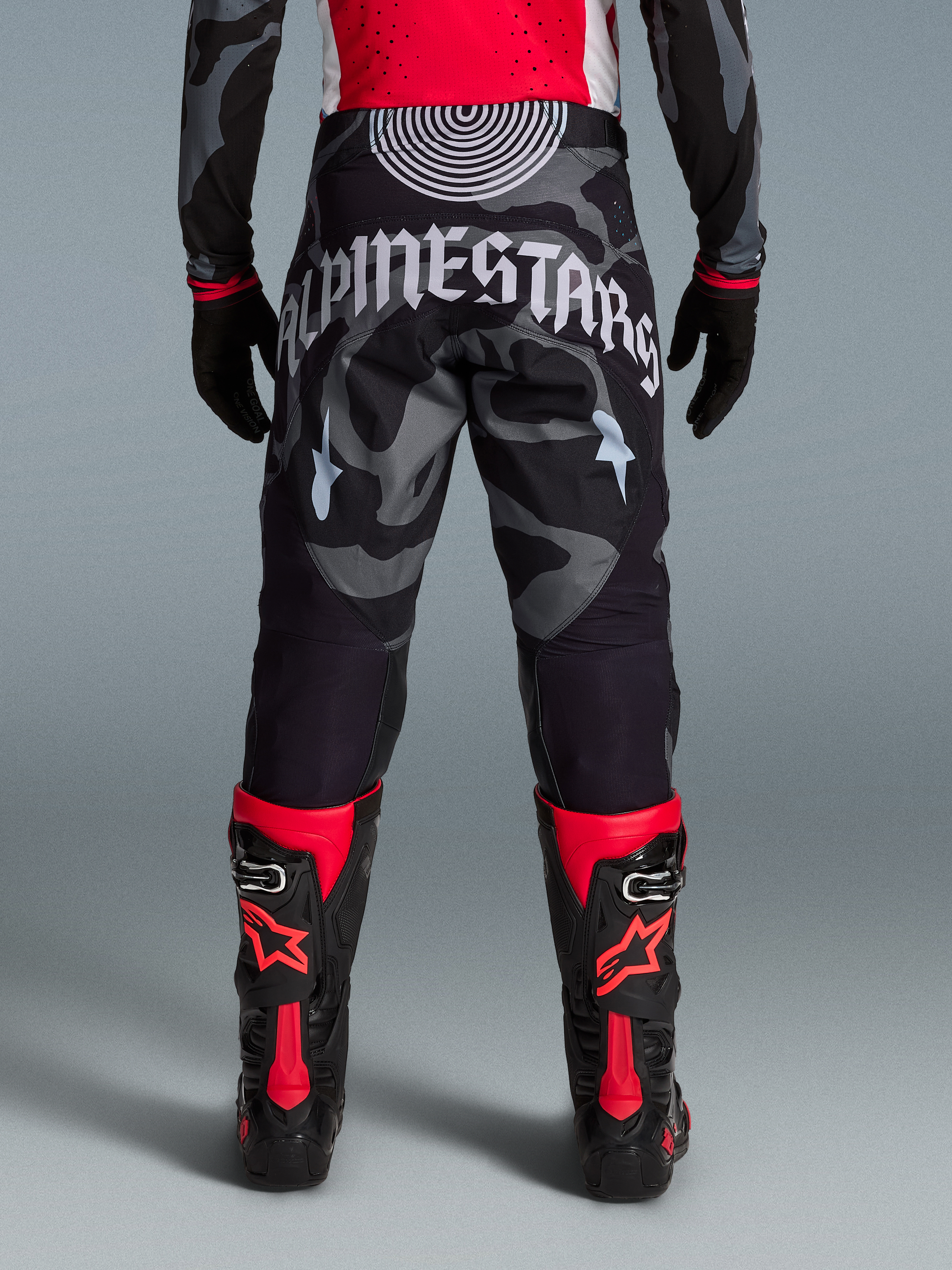 Pantalones Techstar Beast Coast, diseño camuflaje negro y gris con logo grande, botas de motocross en rojo y negro.