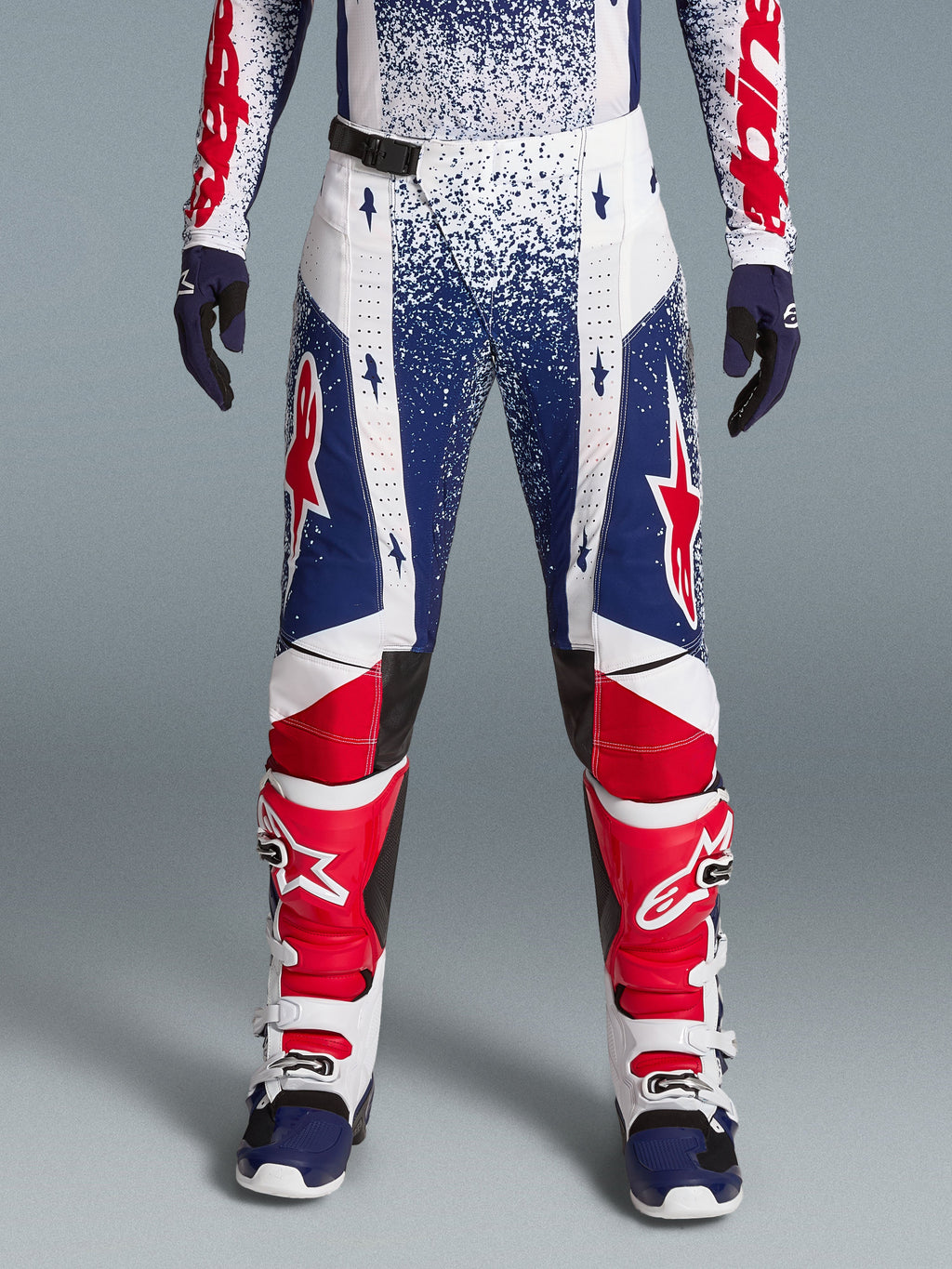 Alpinestars Limited Edition Techstar Unity Gear Set, red, white, and blue speckled motocross pants with racing boots.