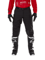 Alpinestars Techdura Pants, Enduro and Off-Road Pants, Black, worn with a red Alpinestars jersey and black and white boots, featuring rugged stretch canvas construction, adjustable magnetic belt buckle, and leather knee reinforcements for off-road performance.