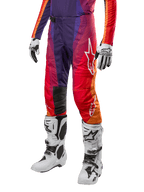 Alpinestars 2024 Techstar Pneuma Pants, pantalones de motocross para hombre con diseño en degradado de púrpura, naranja y azul, logo blanco de Alpinestars, material técnico para alto rendimiento, combinados con botas de motocross blancas y guantes blancos