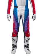Pantalones Alpinestars Techstar Pneuma 2024, pantalones de motocross, en azul, rojo y blanco, con un diseño angular multicolor y detalles en púrpura, combinados con botas de motocross blancas y negras y guantes a juego, corte atlético de competición para rendimiento off-road