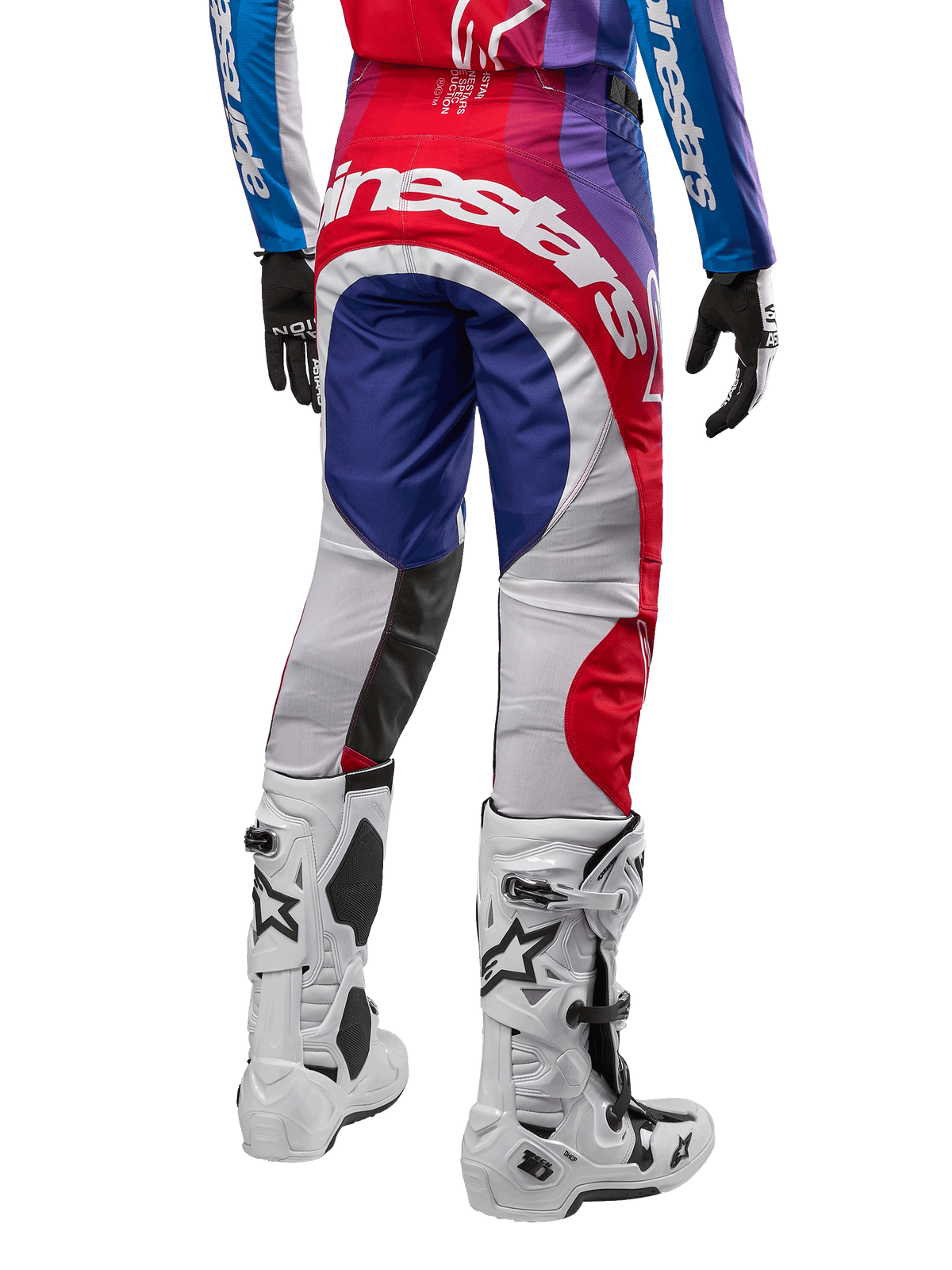 Alpinestars Pantalones Techstar Pneuma 2024, pantalones de motocross, Blu Mars Red White, vista trasera usados con jersey a juego y botas blancas, con logotipo blanco llamativo en el asiento y paneles multicolores, equipamiento profesional de motocross