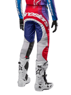 Alpinestars Pantalones Techstar Pneuma 2024, pantalones de motocross, Blu Mars Red White, vista trasera usados con jersey a juego y botas blancas, con logotipo blanco llamativo en el asiento y paneles multicolores, equipamiento profesional de motocross