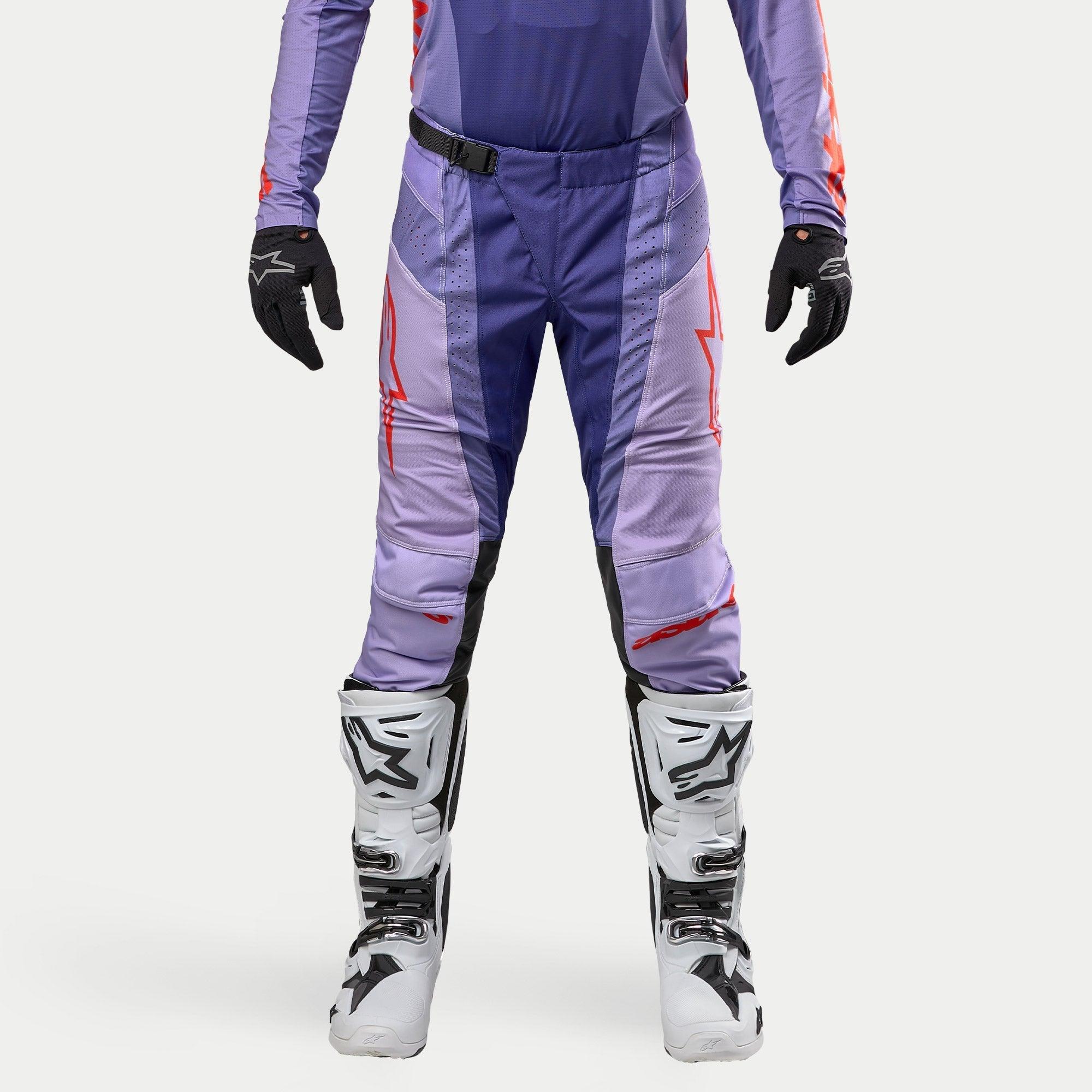 Alpinestars Techstar Ocuri Pants 2024, pantalones de motocross para hombre en color púrpura y naranja intenso, diseño deportivo con logotipos rojos, combinados con guantes negros y botas de motocross blancas y negras, equipamiento de alto rendimiento para off-road.