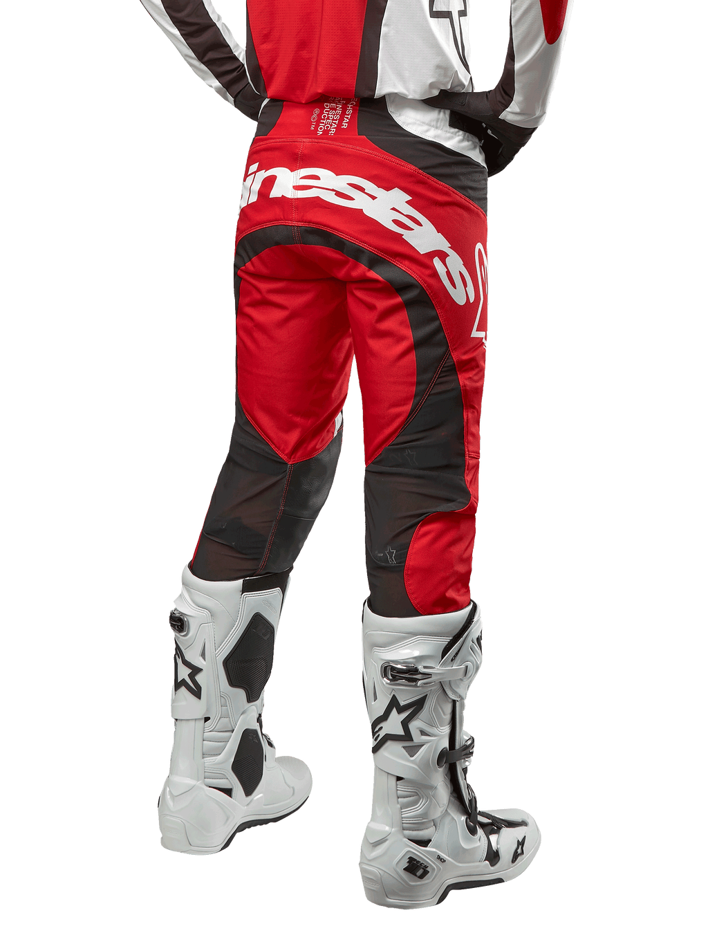 Pantalones Alpinestars Techstar Ocuri 2024, pantalones de motocross, rojo Marte, blanco y negro, vista trasera con un gran logotipo blanco de Alpinestars en la zona del asiento, paneles de ventilación de malla negra, combinados con botas de motocross blancas y negras, diseño de ajuste atlético de competición para conducción todoterreno