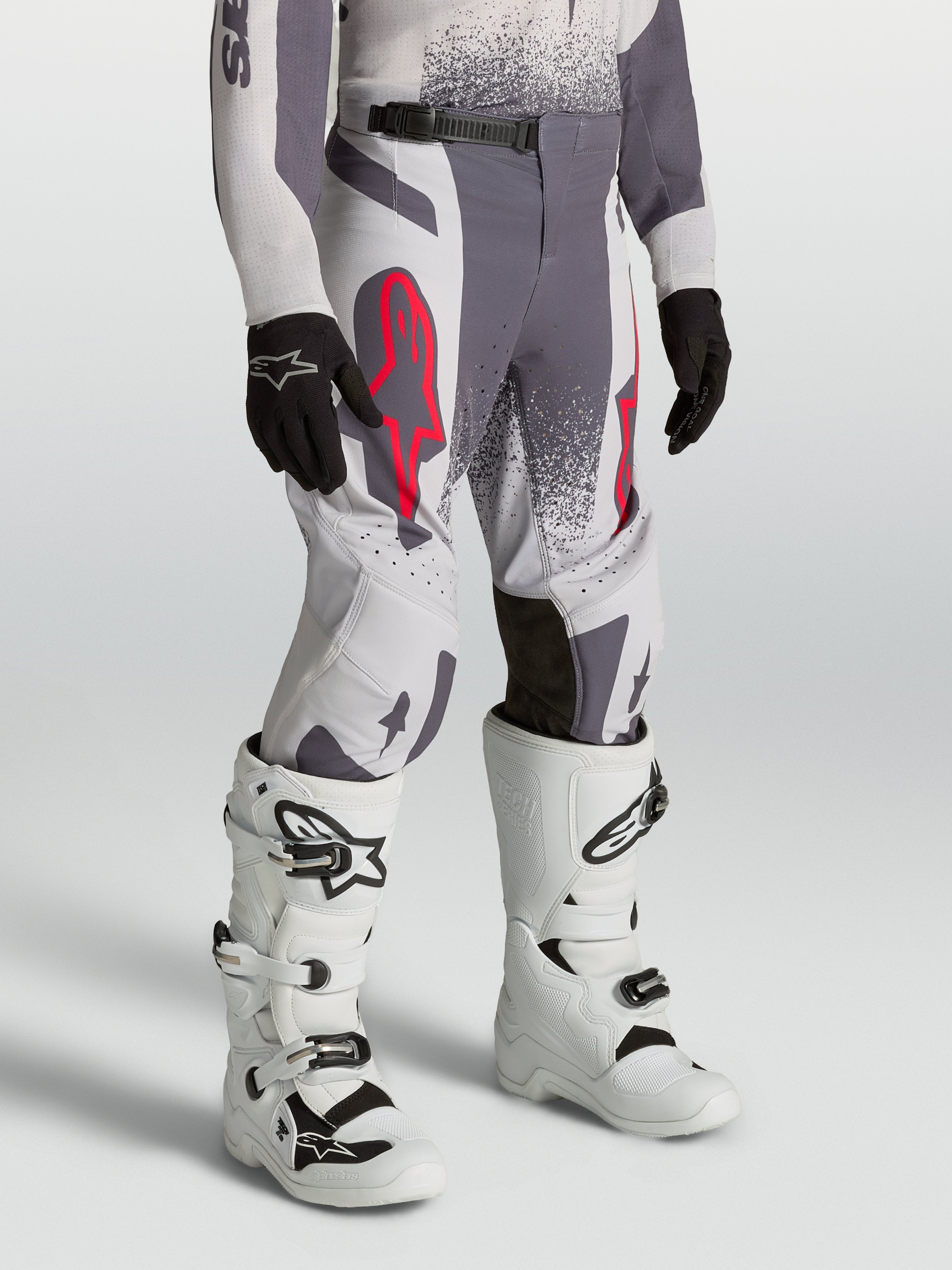Alpinestars pantalones Supertech Swan juveniles, pantalones de motocross gris y lila con detalles rojo flúor y ajuste atlético.