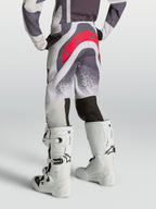 Pantalones Alpinestars Supertech Swan Juveniles, pantalones de motocross para jóvenes, grises y lila con logotipo rojo, vista trasera en modelo.
