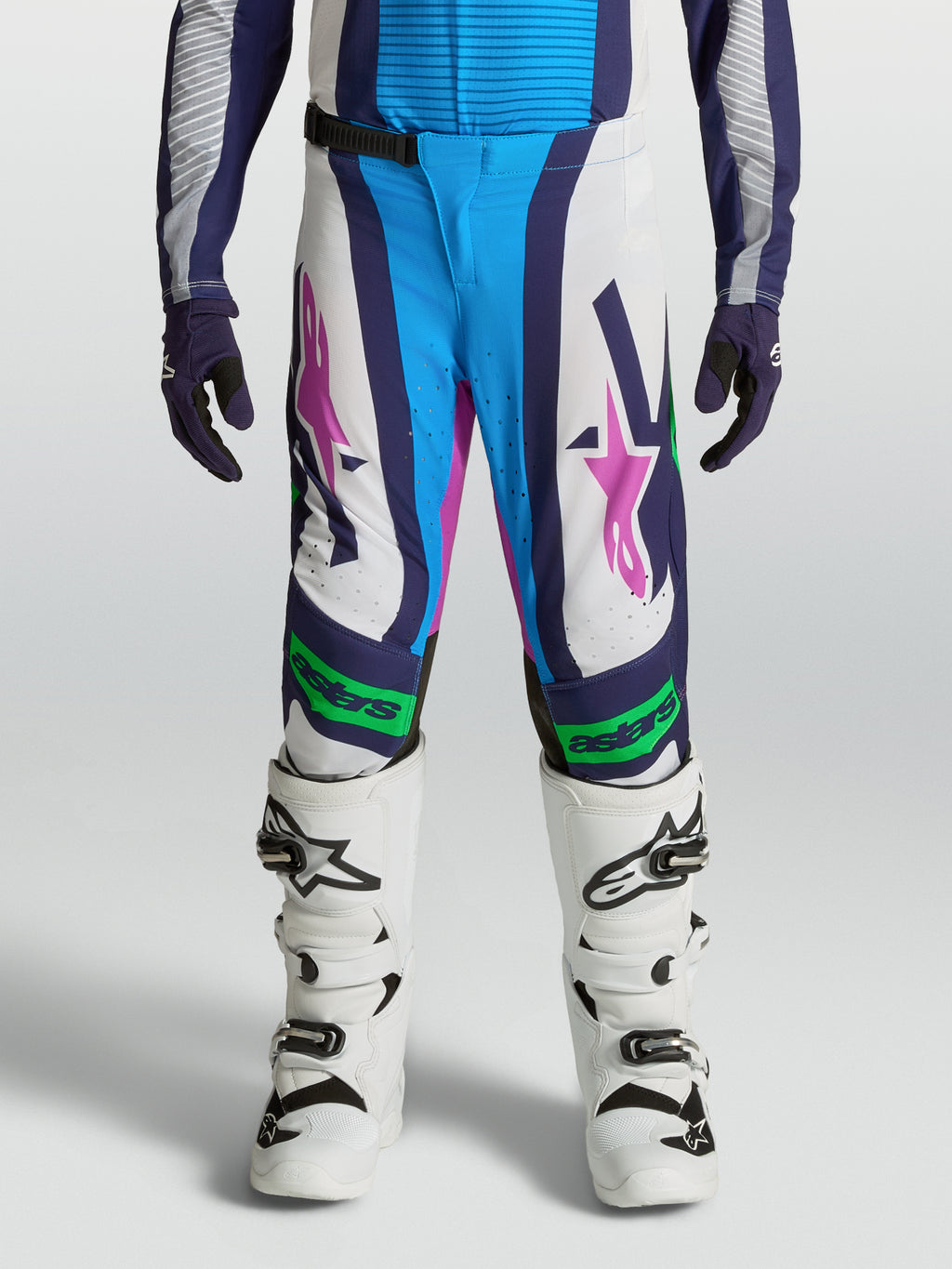 Alpinestars Pantalones Supertech Maven Juvenil, equipo de motocross blanco y azul con detalles verde flúor y rosa.