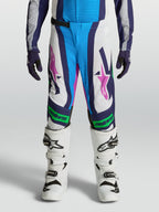 Alpinestars Pantalones Supertech Maven Juvenil, equipo de motocross blanco y azul con detalles verde flúor y rosa.