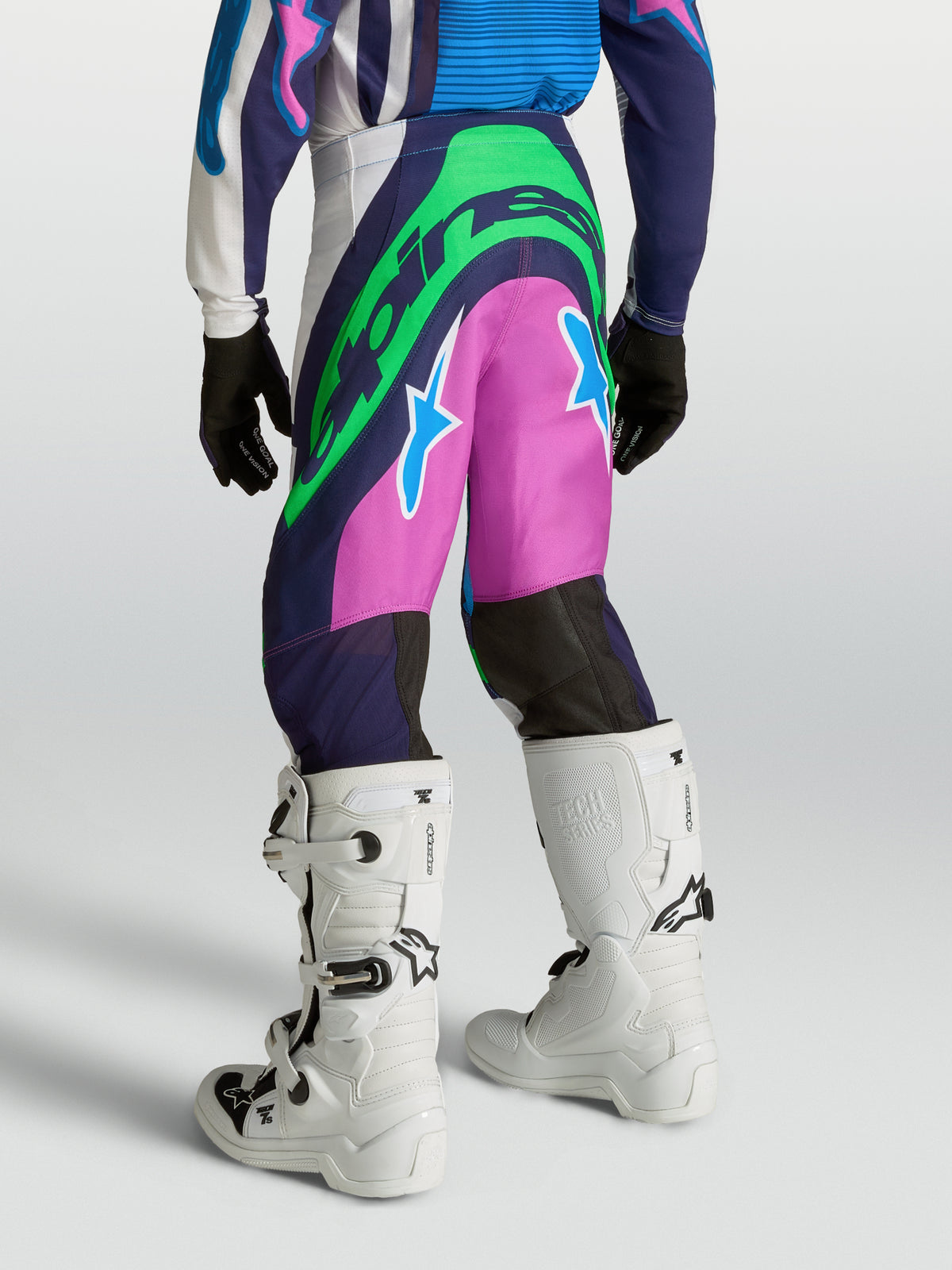 Alpinestars Youth Supertech Maven Motocross Pants in blue and pink with neon green logos, athletic race fit on model.