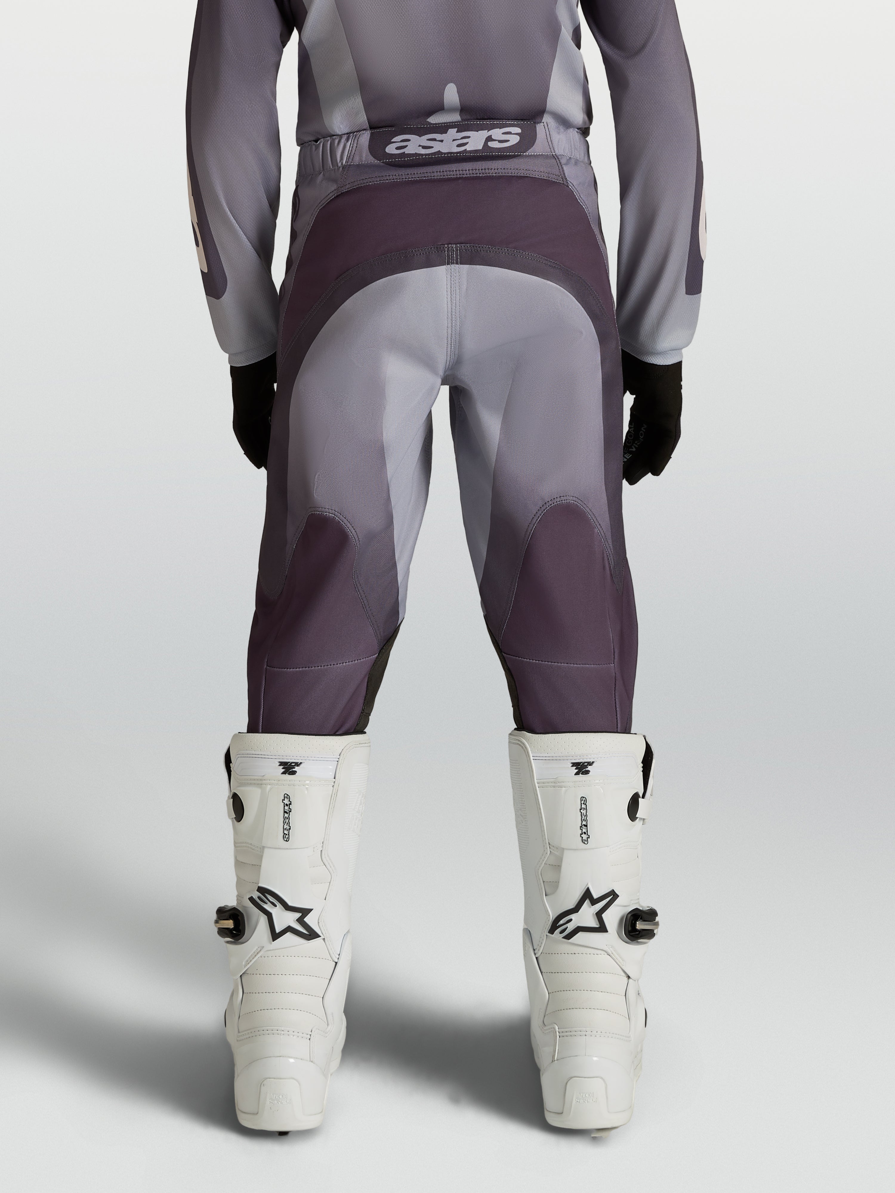 Pantalones de motocross Alpinestars Fluid Amber Juvenil, gris y arena, con refuerzo en el asiento y paneles elásticos.