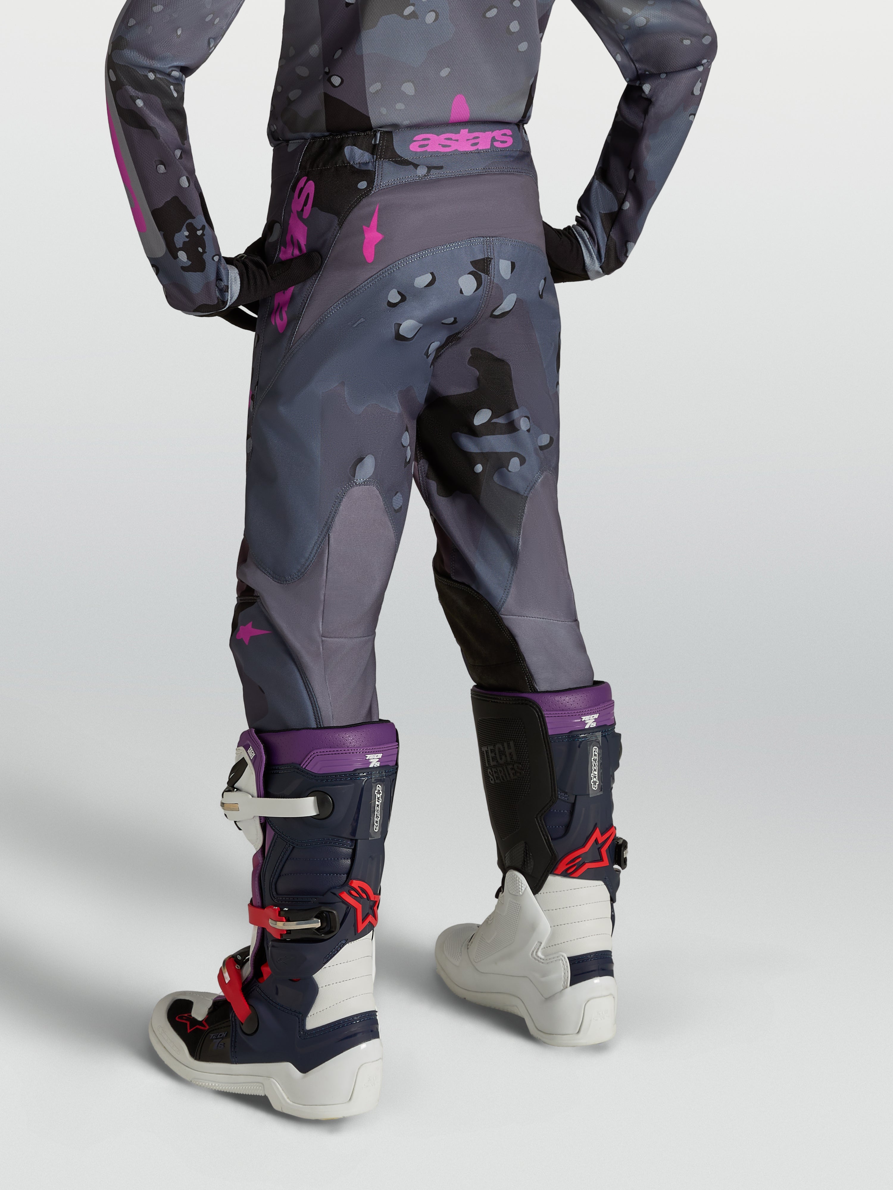 Pantalones Alpinestars Fluid Lone juveniles, de motocross, gris camuflaje y morados, vista trasera en modelo.
