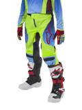 Alpinestars Pantalones Racer Hoen Juveniles 2024, pantalones de motocross, amarillo fluorescente y azul marino noche con detalles rojos, usados con guantes a juego y botas blancas, negras y rojas, con ajuste deportivo y piernas precurvadas para carreras todoterreno