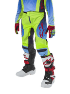 Alpinestars Pantalones Racer Hoen Juveniles 2024, pantalones de motocross, amarillo fluorescente y azul marino noche con detalles rojos, usados con guantes a juego y botas blancas, negras y rojas, con ajuste deportivo y piernas precurvadas para carreras todoterreno