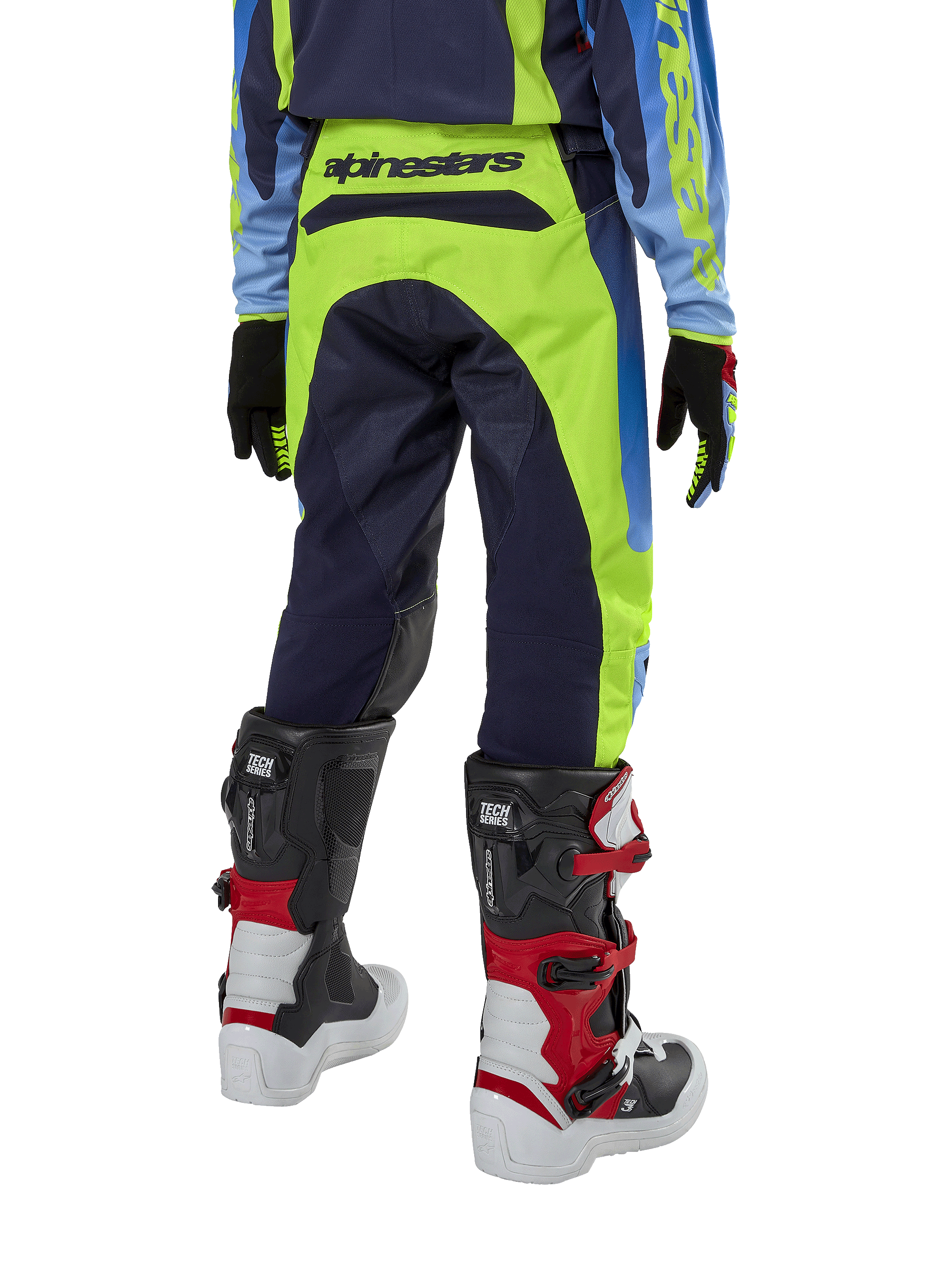 Pantalones Alpinestars Youth 2024 Racer Hoen, pantalones de motocross, amarillo flúor y azul noche, vista trasera con marca Alpinestars destacada en la cintura, usados con botas Tech Series negras y rojas y jersey a juego, diseño deportivo duradero para conducción off-road juvenil