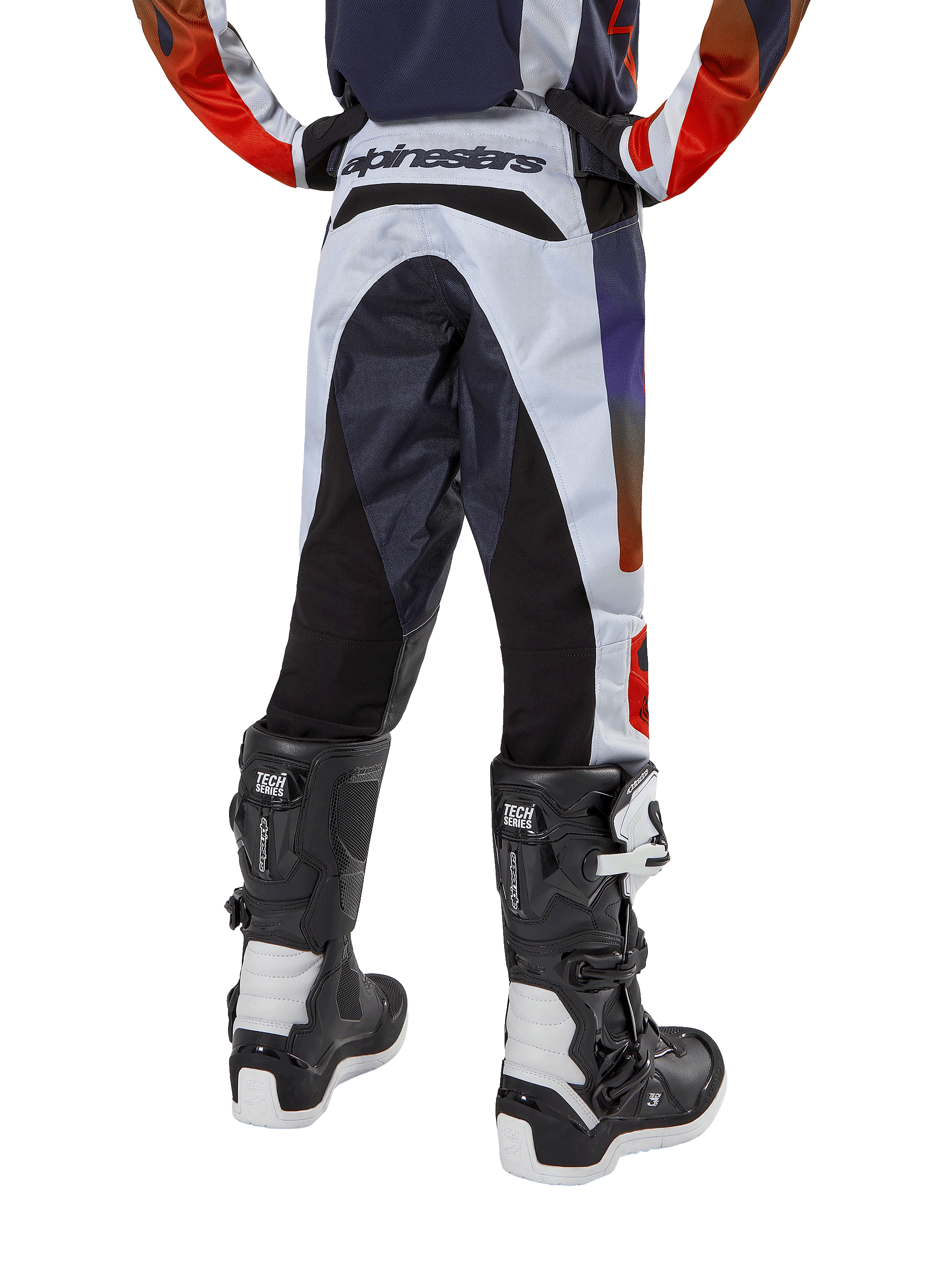 Alpinestars 2024 Youth Racer Hoen Pants, pantalones de motocross juveniles, gris claro con detalles en naranja intenso y negro, vista trasera con paneles negros en el asiento y las piernas, marca destacada en la parte trasera de la cintura, combinados con botas de motocross blancas y negras para carreras todoterreno
