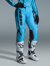 Alpinestars 2026 Stella Fluid Apex Pants para mujer, pantalones de motocross, azul brillante con logotipos en negro, usados con jersey a juego, guantes negros y botas de motocross blancas y negras, diseño ergonómico para un alto rendimiento