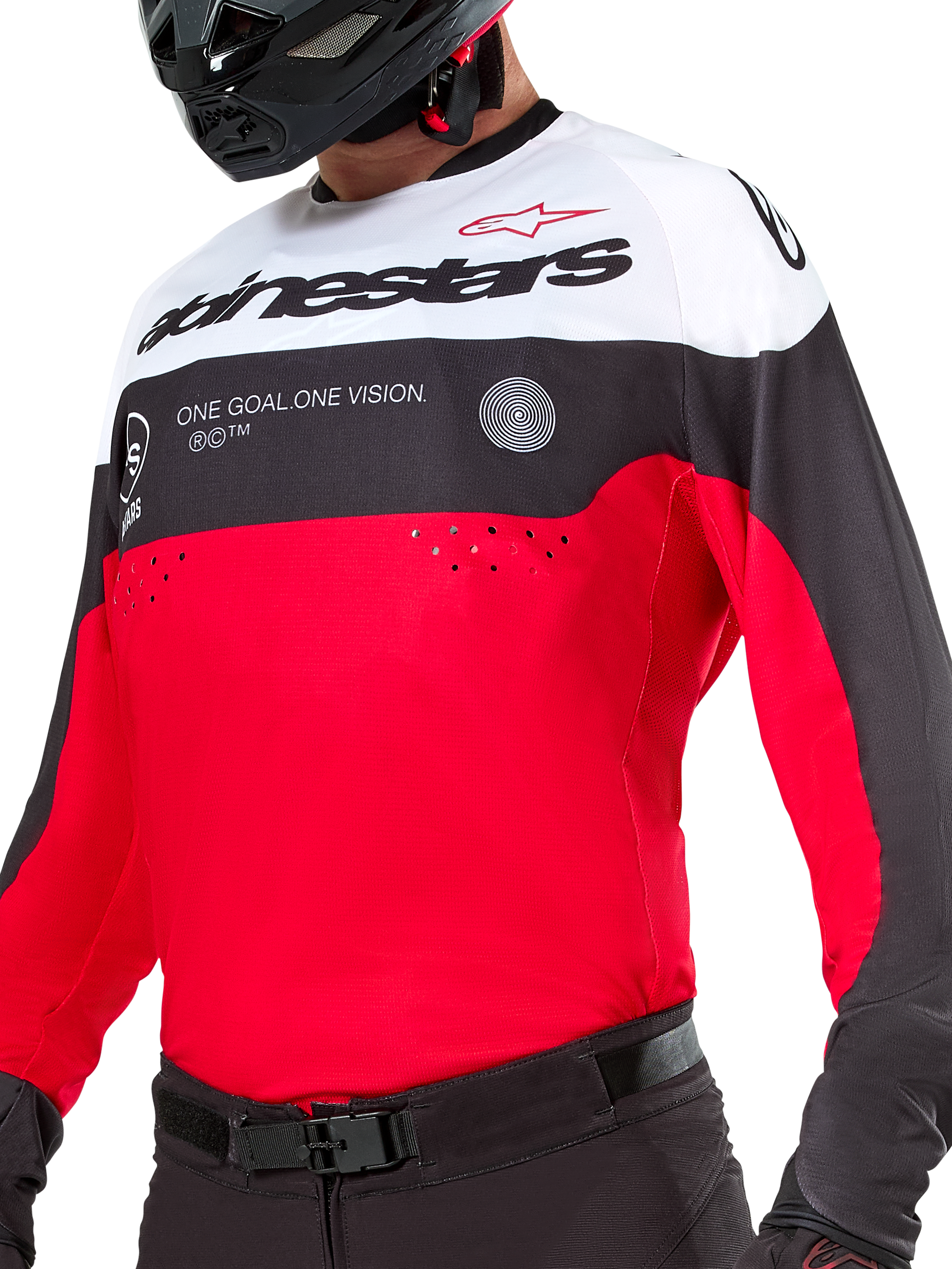 Jersey Alpinestars Pro-Dura, jersey de motocross y enduro, negro, rojo brillante y blanco, con gráfico 'ONE GOAL. ONE VISION.' y perforaciones láser en el pecho, usado con pantalones de motocross negros y casco.
