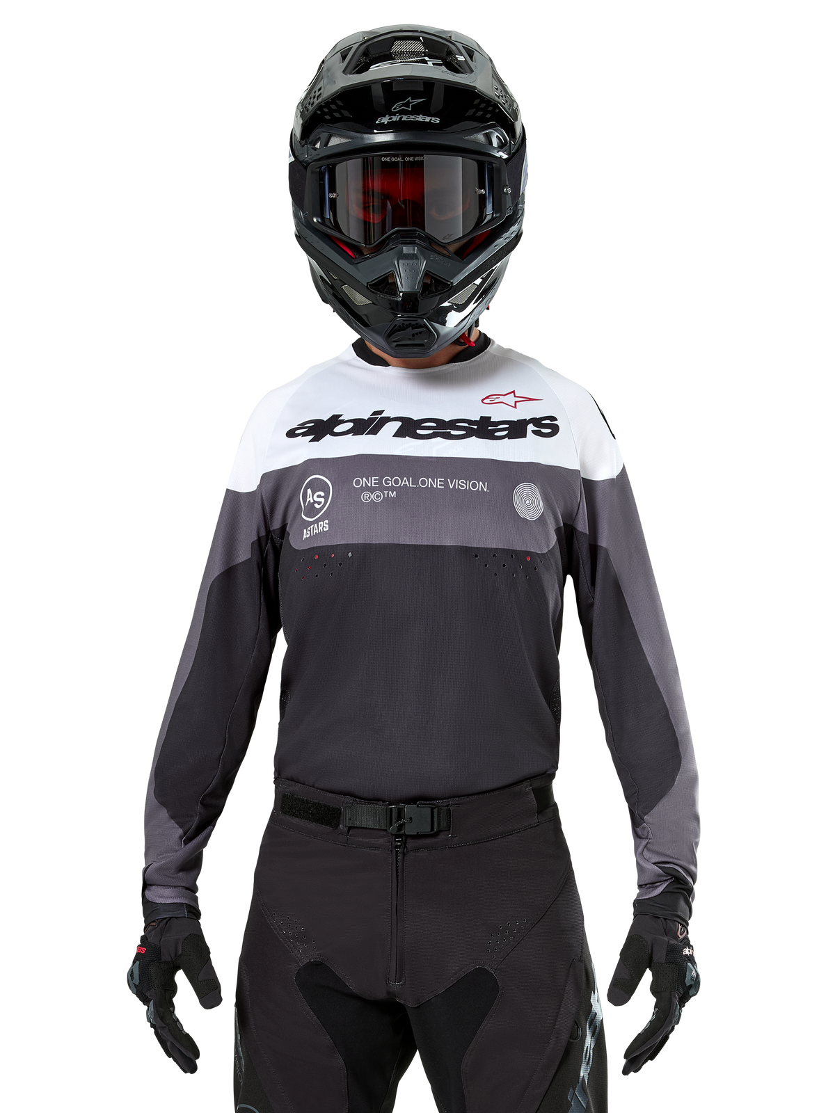 Motocross rider wearing the Alpinestars Pro-Dura Jersey in Black Magnet White, long-sleeve performance top with white and grey color blocks, worn with a black helmet and goggles, featuring 'alpinestars' branding and 'ONE GOAL ONE VISION' slogan, off-road motorcycle racing apparel