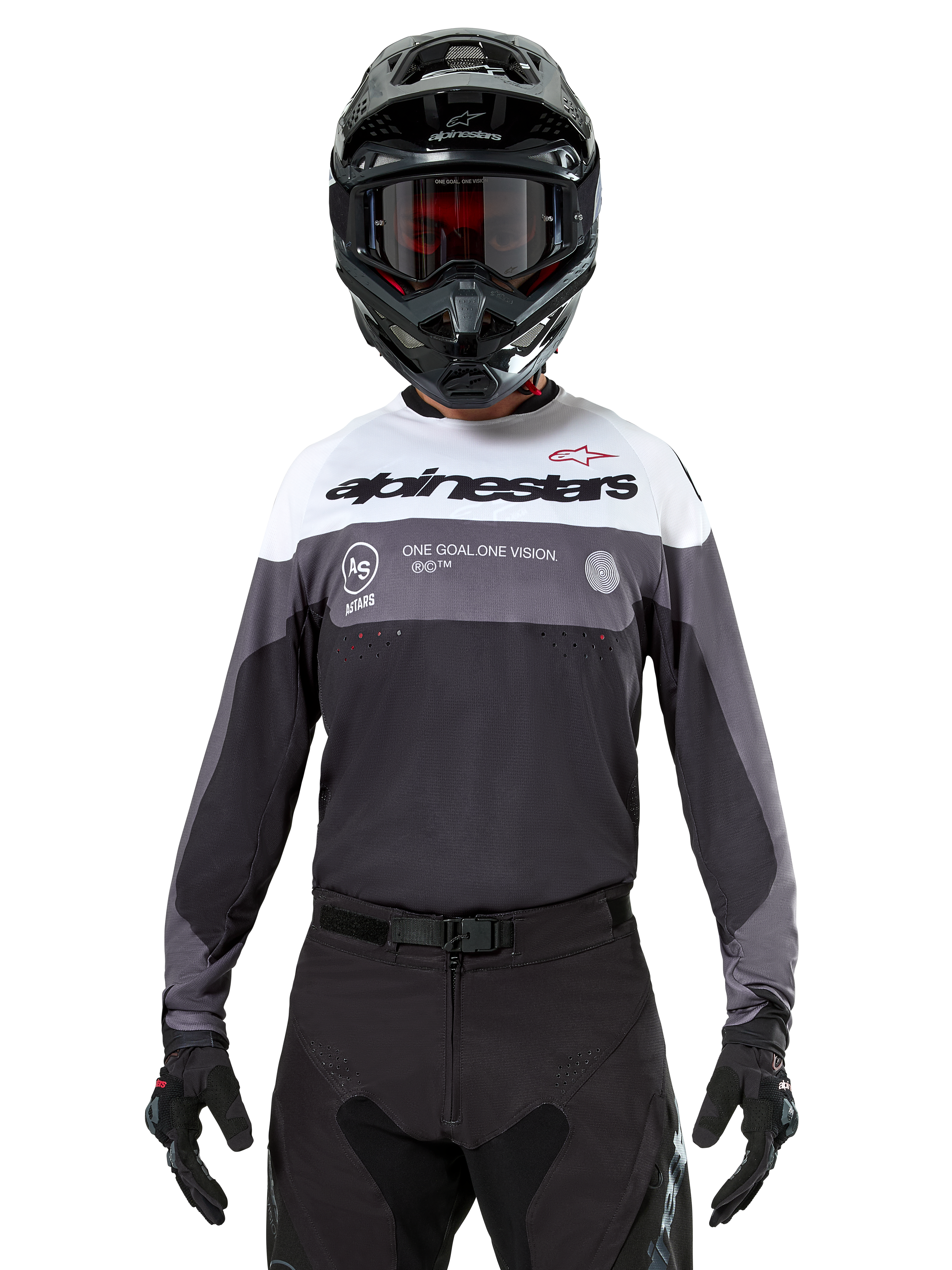 Piloto de motocross con el jersey Alpinestars Pro-Dura en Black Magnet White, camiseta técnica de manga larga con bloques de color blanco y gris, usada con casco negro y gafas, con marca 'alpinestars' y el eslogan 'ONE GOAL ONE VISION', equipamiento de competición para motociclismo off-road