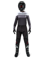 Piloto de motocross con equipamiento completo de competición, Jersey Pro-Dura en color Black Magnet White con la parte superior del pecho blanca y detalles en gris, combinado con pantalones negros, casco negro con gafas oscuras, botas blancas y negras y guantes negros, conjunto coordinado para enduro y carreras off-road.
