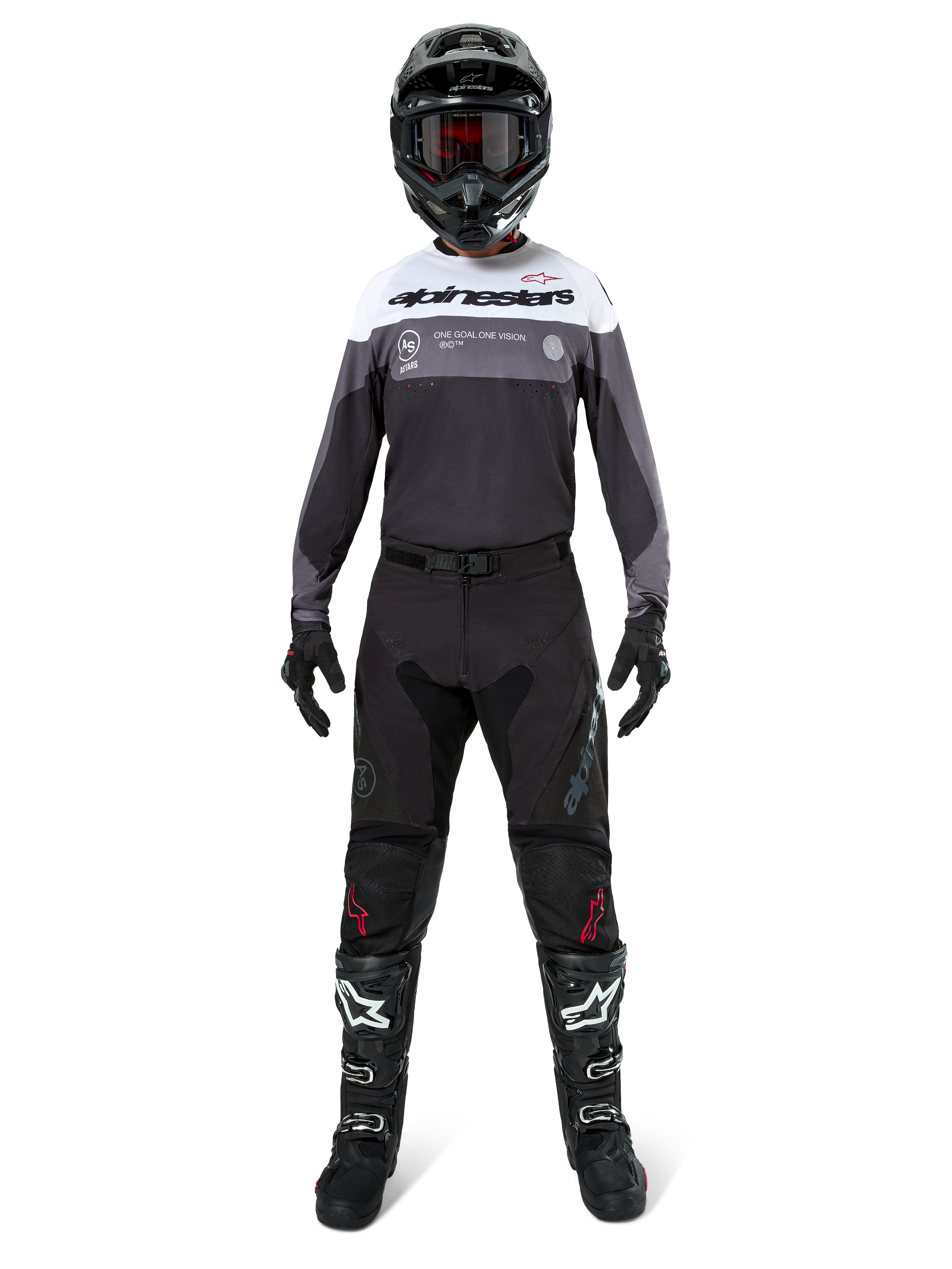 Piloto de motocross con equipamiento completo de competición, Jersey Pro-Dura en color Black Magnet White con la parte superior del pecho blanca y detalles en gris, combinado con pantalones negros, casco negro con gafas oscuras, botas blancas y negras y guantes negros, conjunto coordinado para enduro y carreras off-road.