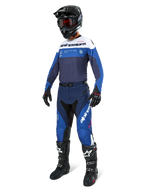 Motocross rider wearing complete racing gear, Pro-Dura Jersey in Navy Bright Blue and White, matching blue and navy pants, black helmet with red goggles, black boots with white accents, and black gloves, coordinated outfit for enduro and off-road riding