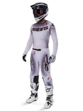 Alpinestars Supertech Maker Gear Set 2025, conjunto completo de motocross, degradado blanco y gris con logotipos negros y detalles rojos, incluye casco con gafas, jersey, pantalones, botas blancas y guantes, diseño aerodinámico de alto rendimiento para carreras off-road