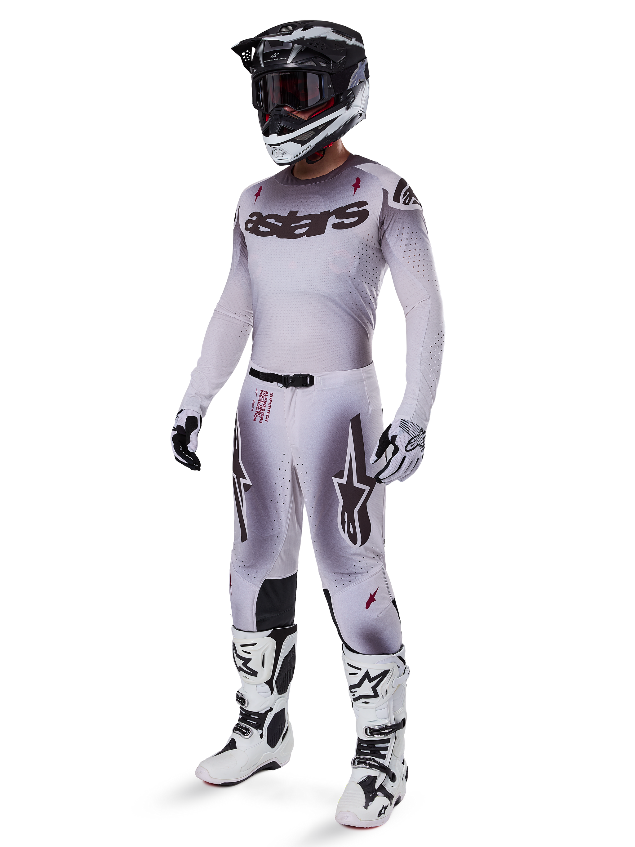 Motocross rider wearing the Alpinestars 2025 Supertech Maker Jersey in Silver and Black, matching silver and black pants, black and white helmet with black goggles, white and black boots, and coordinating gloves, professional gradient design for off-road racing