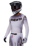Jersey Alpinestars Supertech Maker 2025, jersey de competición de motocross, degradado en plata y negro, malla elástica transpirable con perforaciones cortadas por láser, usado con pantalones y casco a juego, con marca 'astars', equipamiento profesional completo para off-road