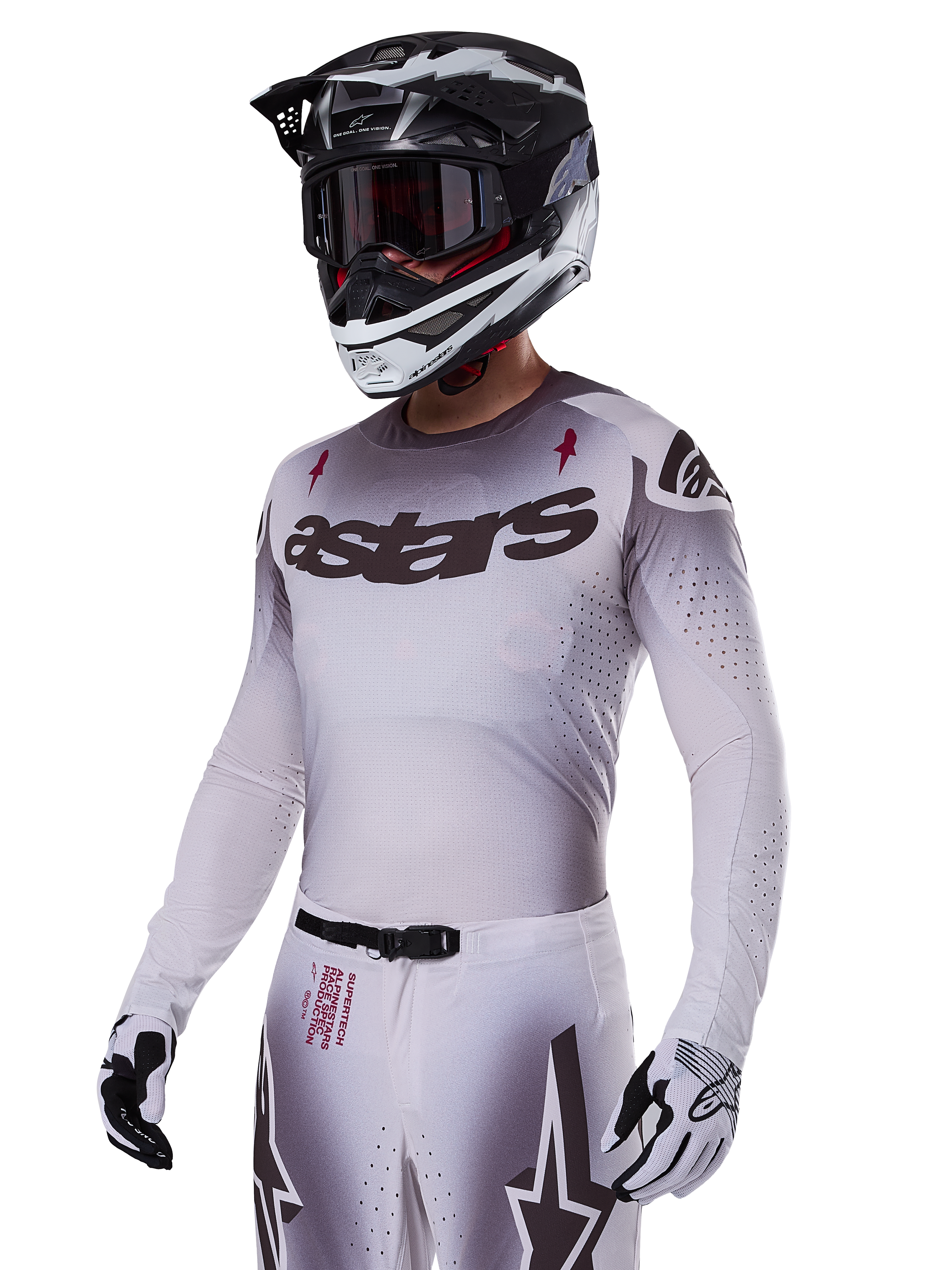 Jersey Alpinestars Supertech Maker 2025, jersey de competición de motocross, degradado en plata y negro, malla elástica transpirable con perforaciones cortadas por láser, usado con pantalones y casco a juego, con marca 'astars', equipamiento profesional completo para off-road