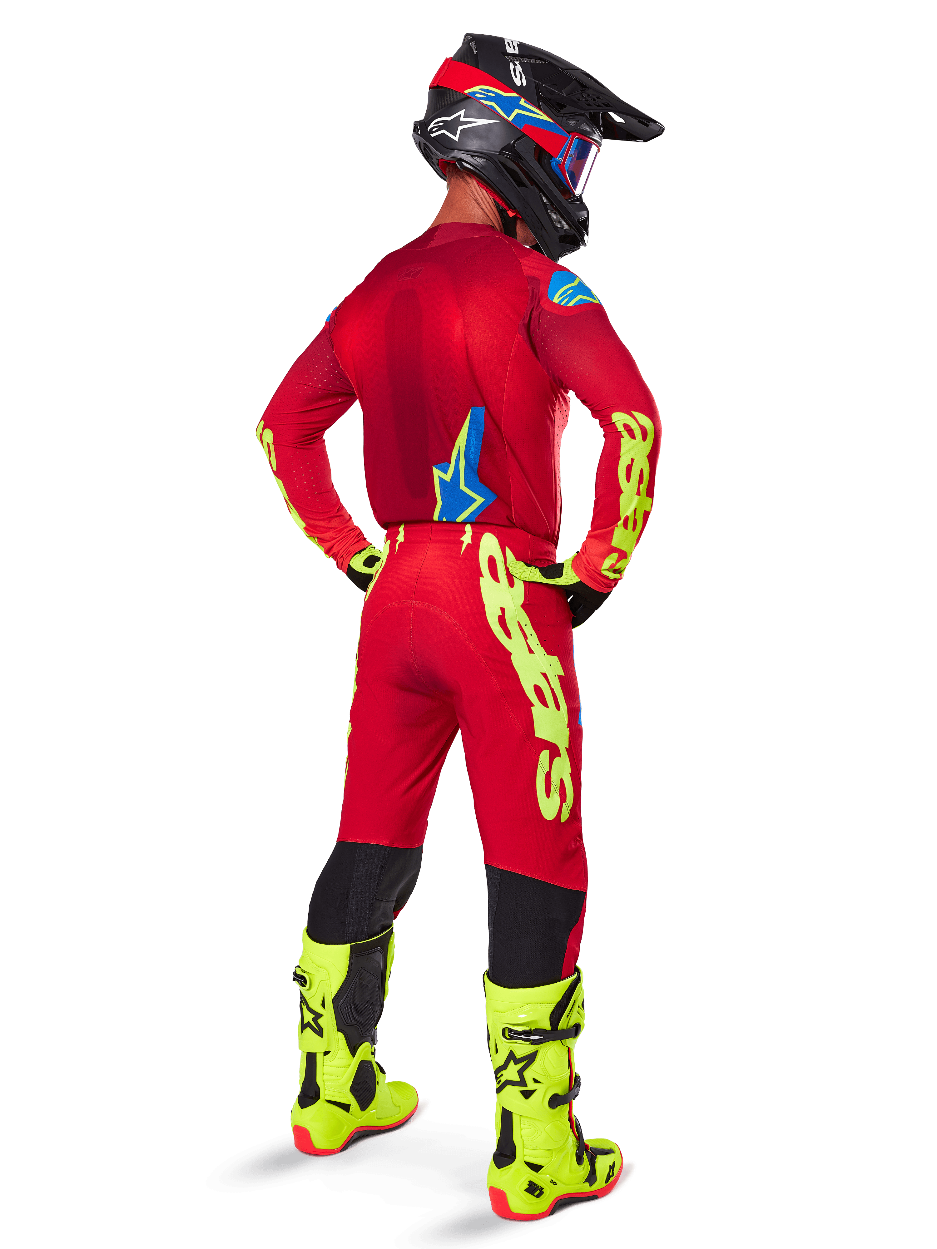 Motocross rider from a rear view wearing the Alpinestars 2025 Supertech Maker Gear Set, Bright Red jersey with yellow fluo branding, matching red pants with yellow accents, black helmet with red and blue details, fluo yellow boots, coordinated professional racing outfit for off-road performance.